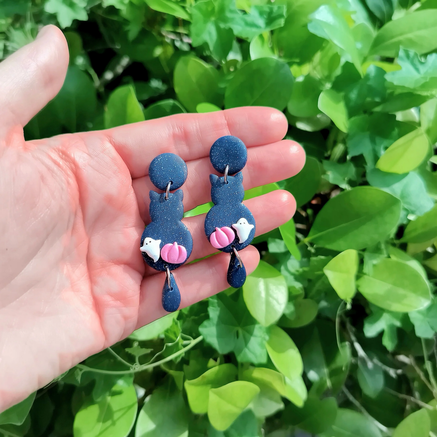 polymer clay cat earrings made of sparkle midnight blue with tiny ghosts and tiny pumpkins