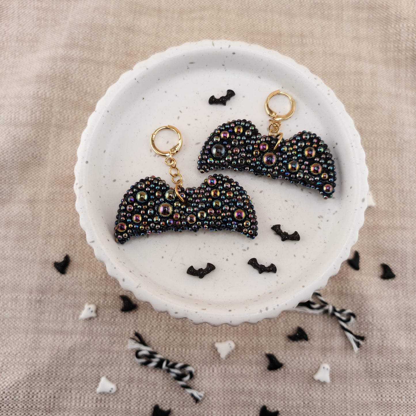 Black beaded earrings with gold hooks on a white dish with Halloween-themed decorations.
