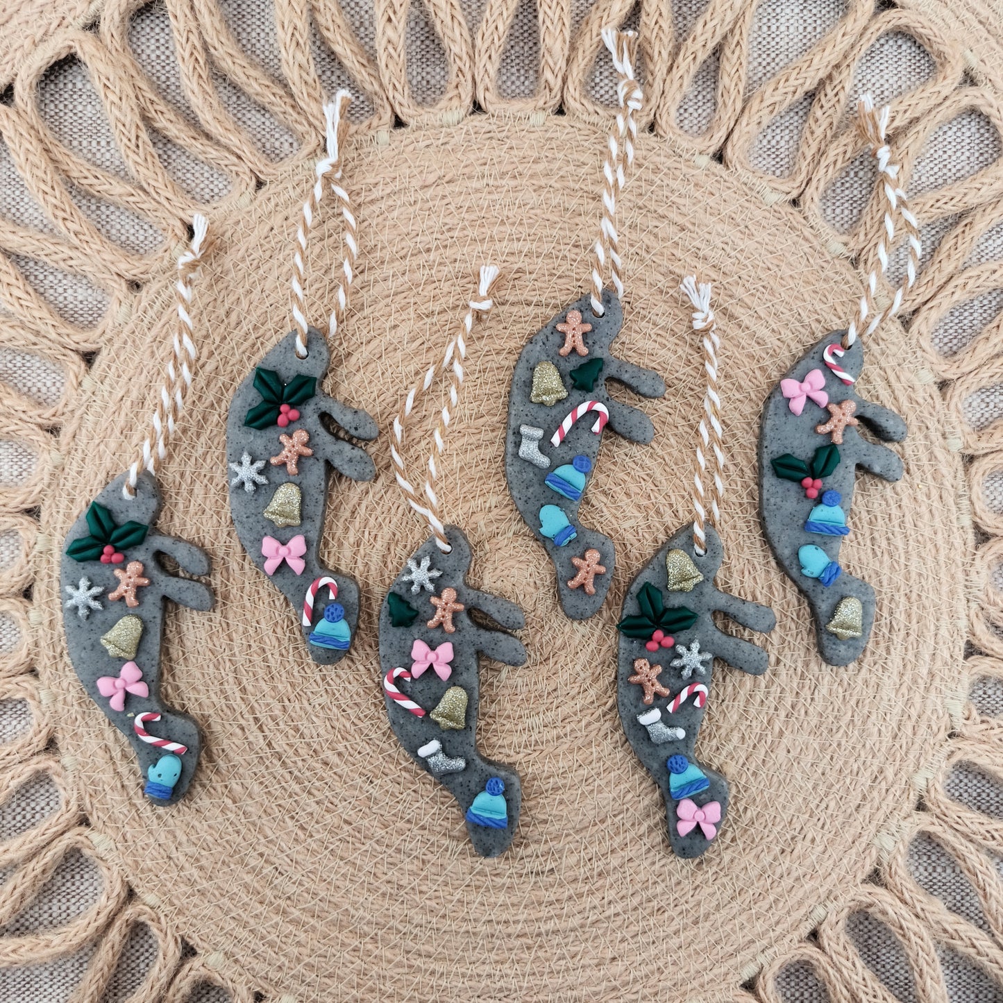 Decorative ornaments shaped like manatees with colorful embellishments on a textured woven surface.