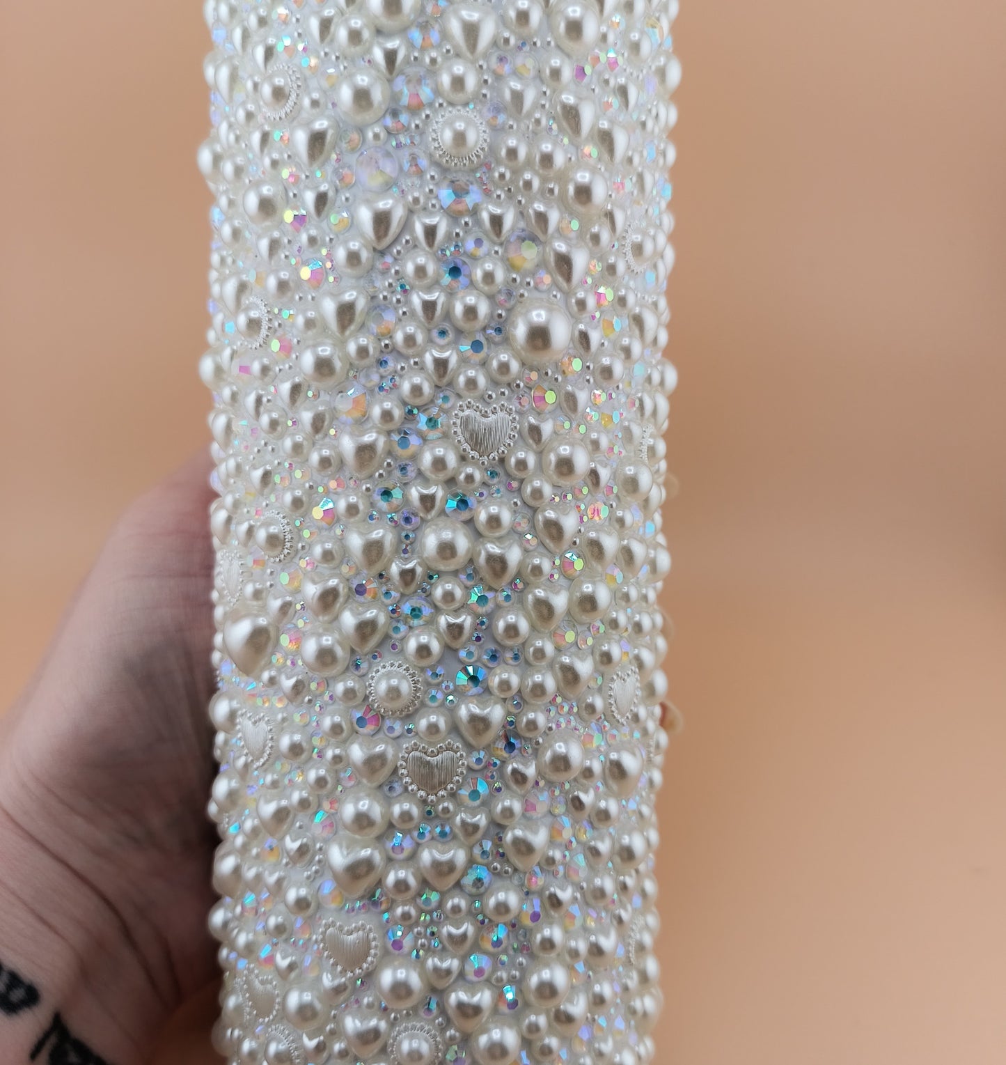 20 oz tumbler covered in pearls held by a hand against a beige background