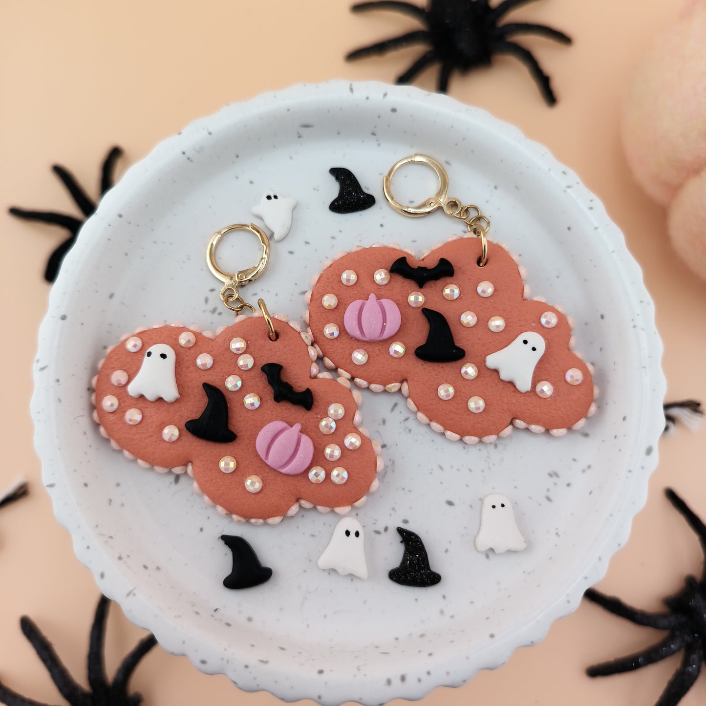 Halloween-themed earrings on a white plate with spider webs in the background
