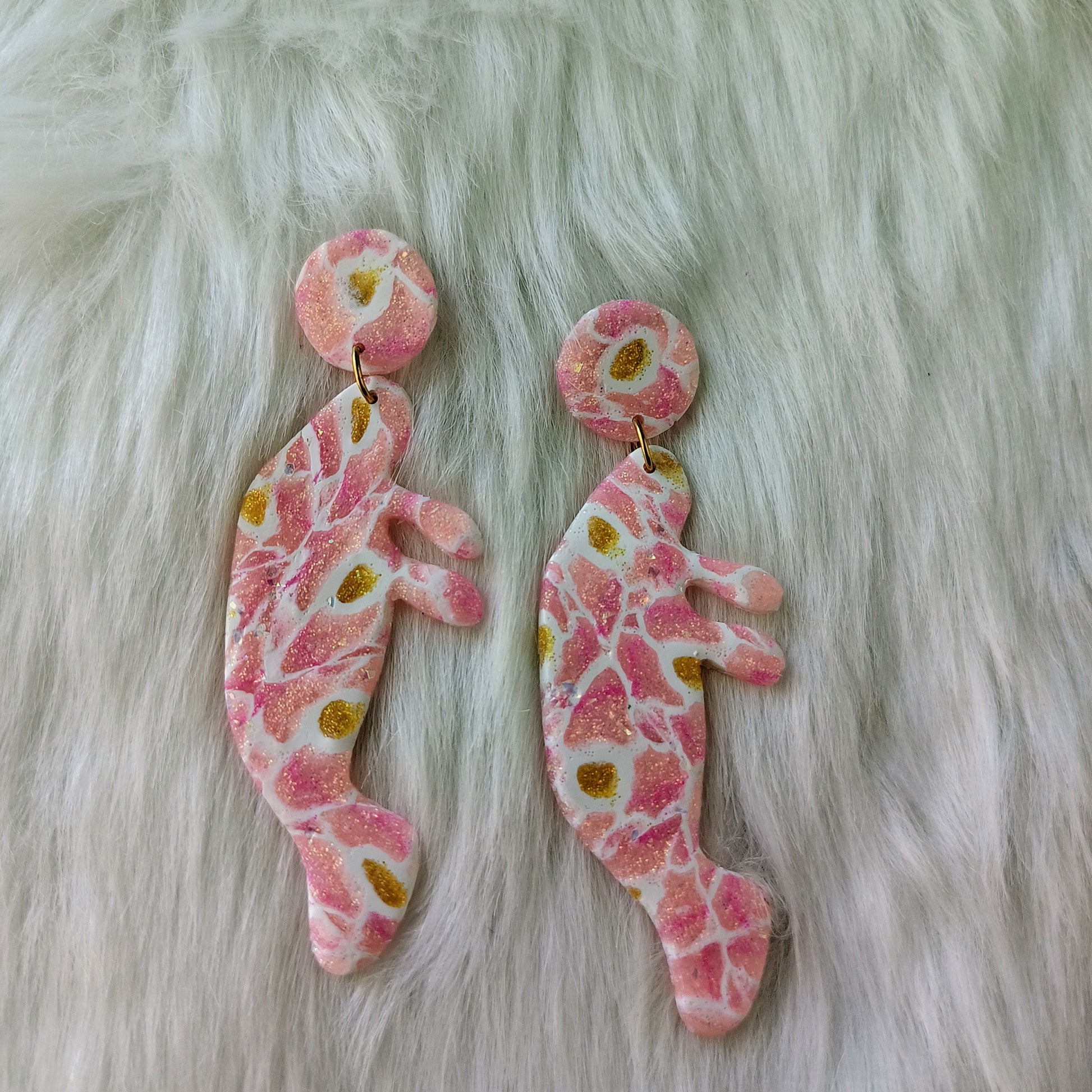 Pair of pink floral manatee earrings on a fur surface
