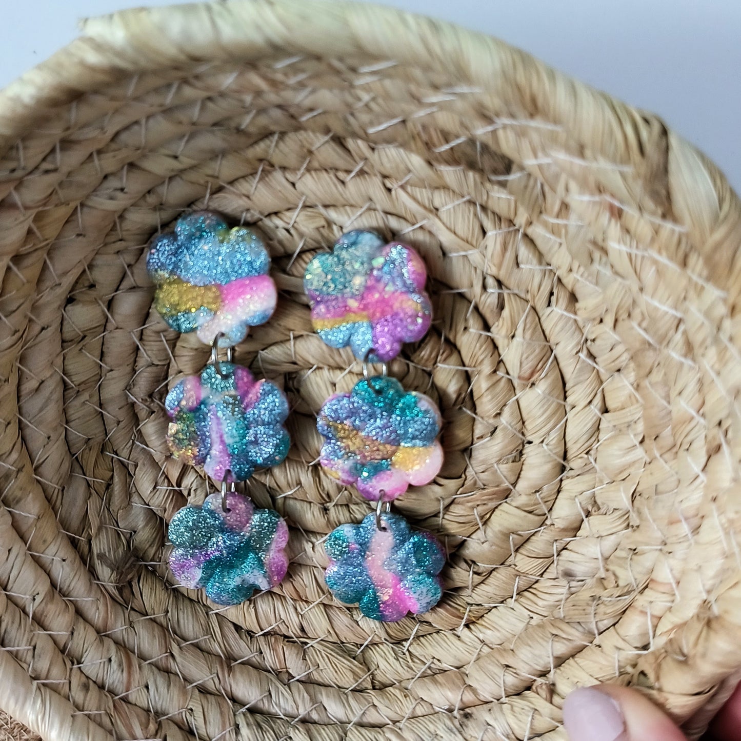 Colorful, sparkle flower-shaped earrings on a woven basket
