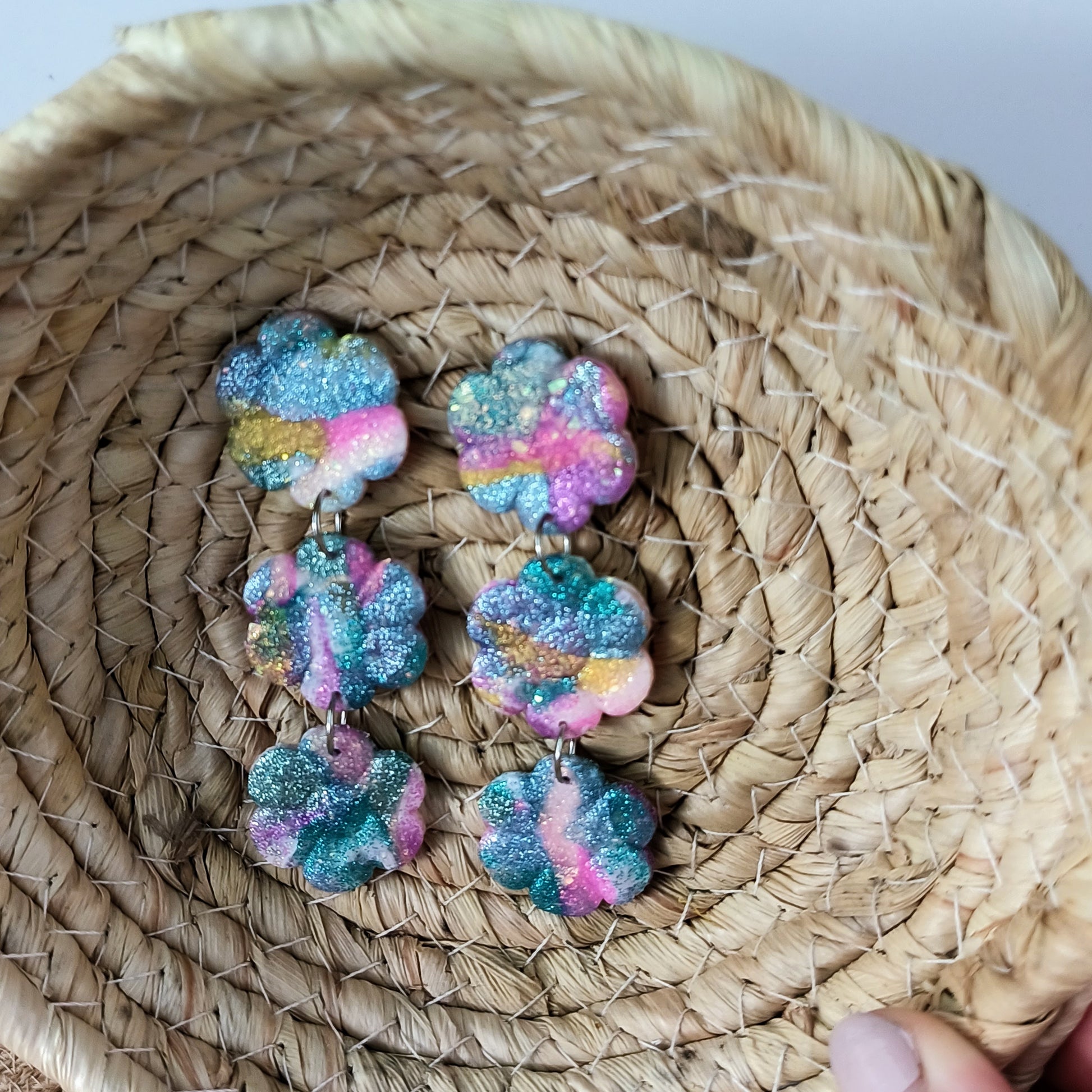 Colorful, sparkle flower-shaped earrings on a woven basket