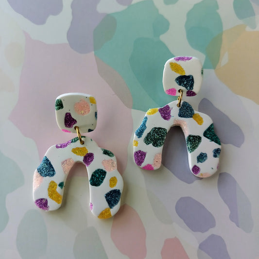 Colorful sparkle abstract patterned earrings on a multicolored background