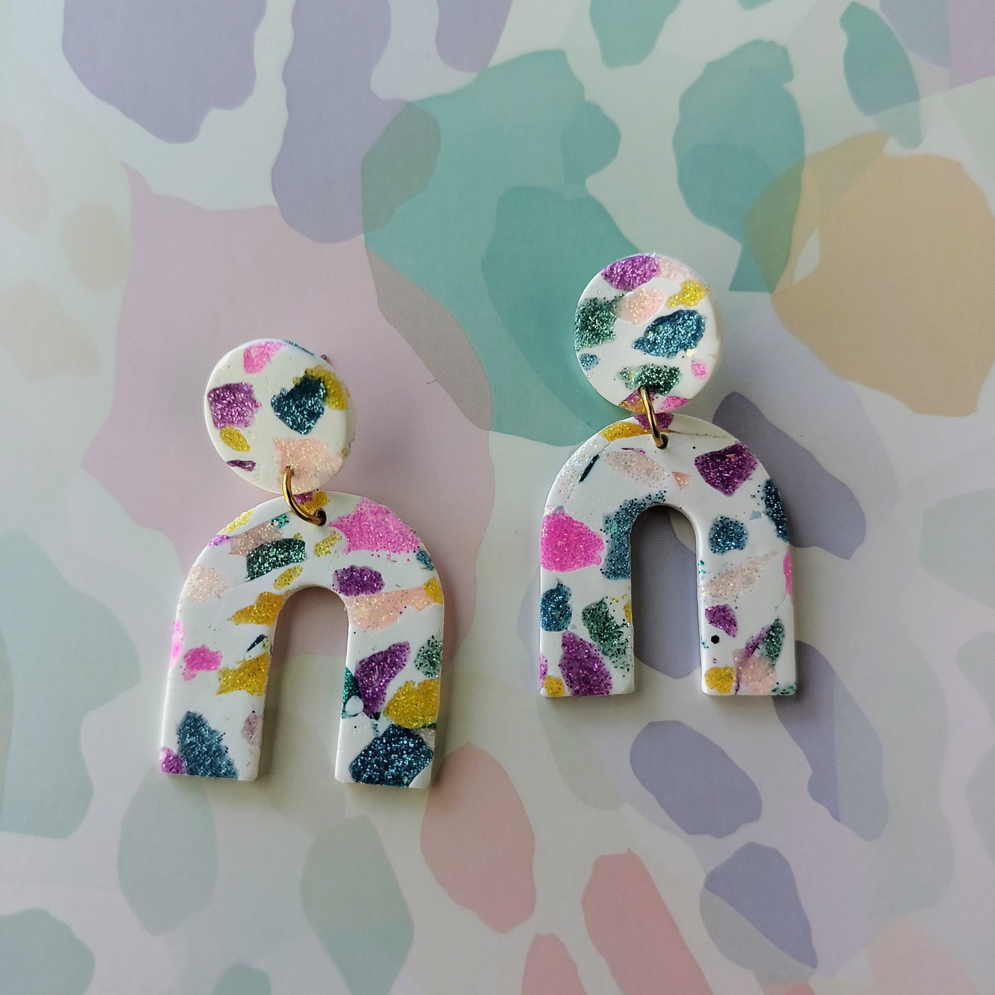 Colorful abstract patterned earrings on a multicolored background