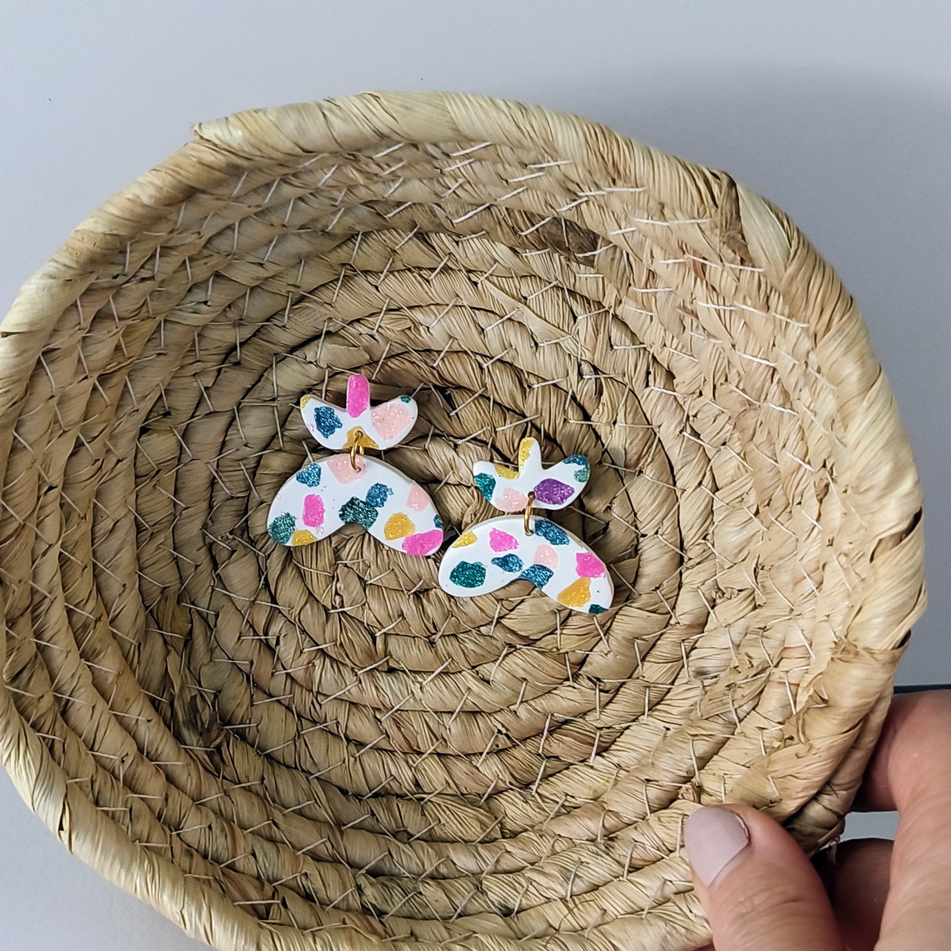 Colorful butterfly-shaped earrings on a woven basket