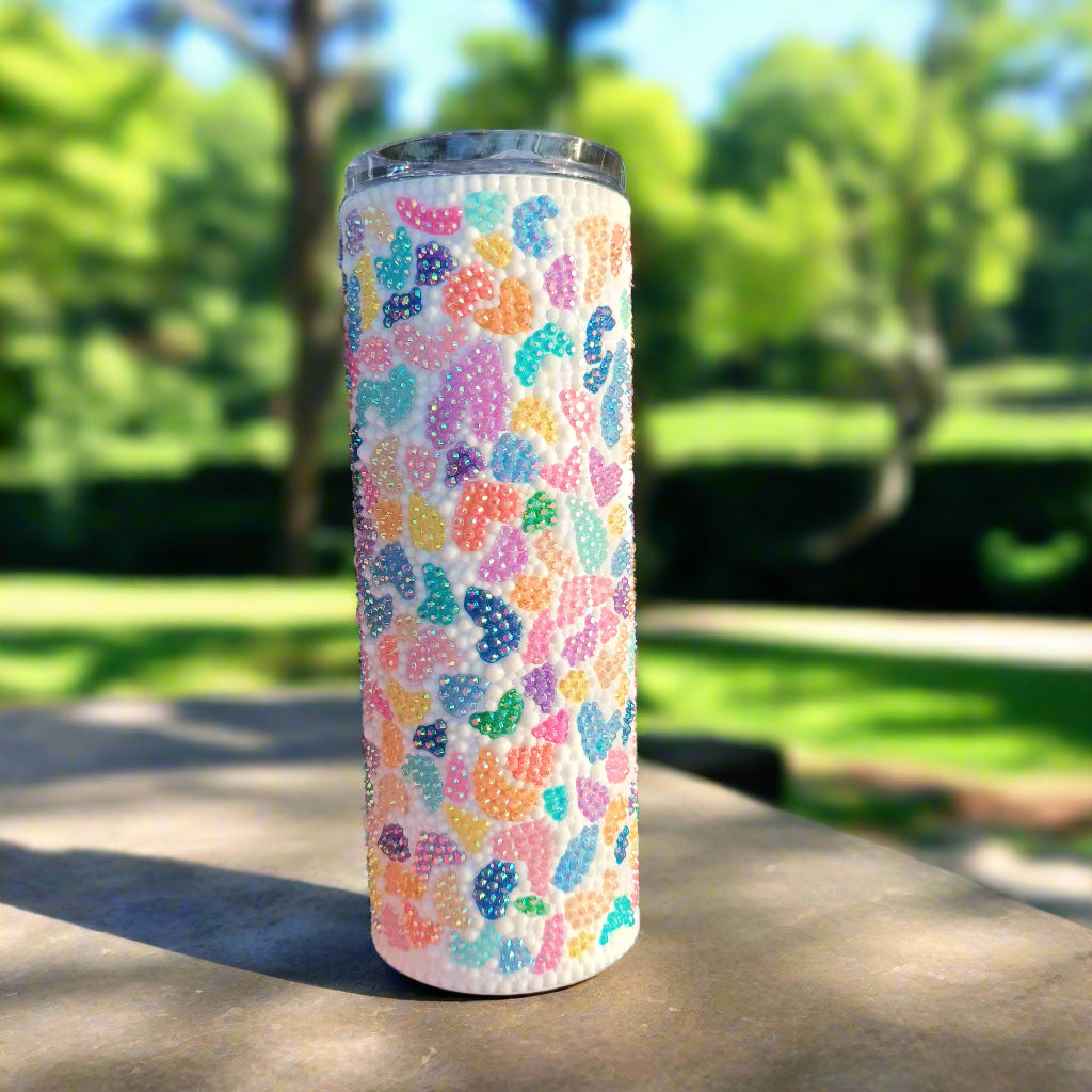 Rainbow terrazzo bedazzled tumbler with a natural background