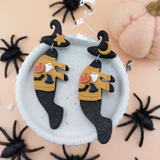 Halloween-themed manatee earrings on a white dish with spider decorations.