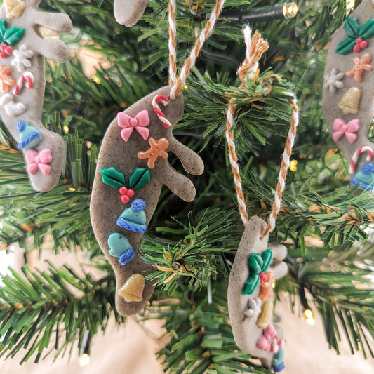 Decorative Christmas ornaments shaped like manatees with colorful details on a tree.