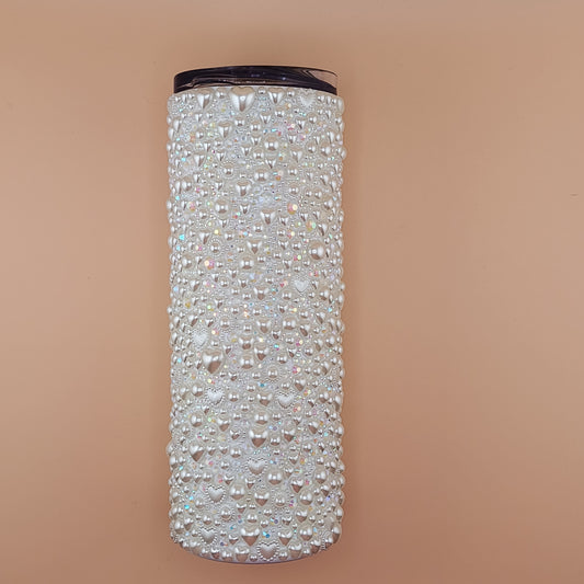 20 oz tumbler covered in heart pearls and rhinestones on a beige background