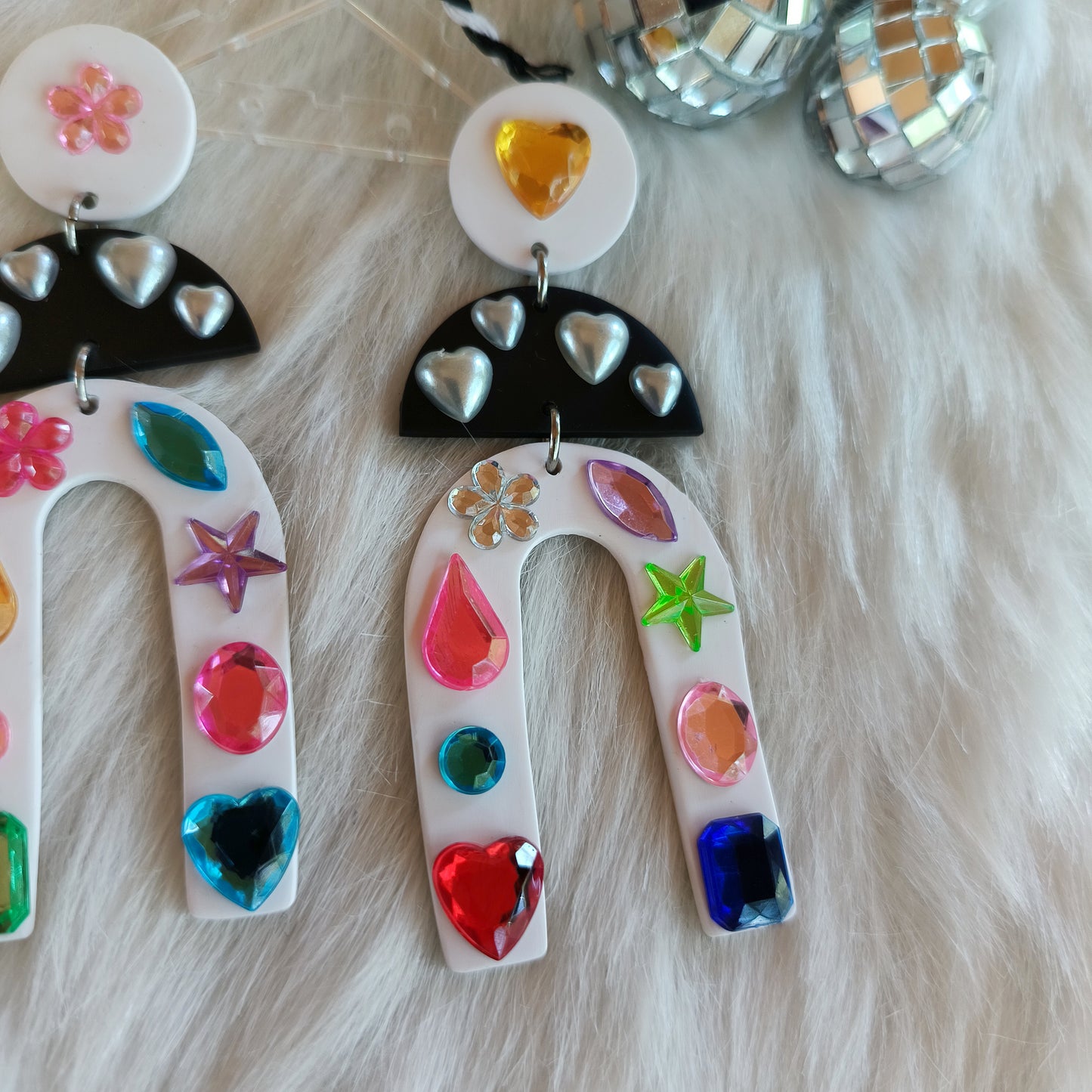 Colorful earrings with heart and star designs on a soft background.