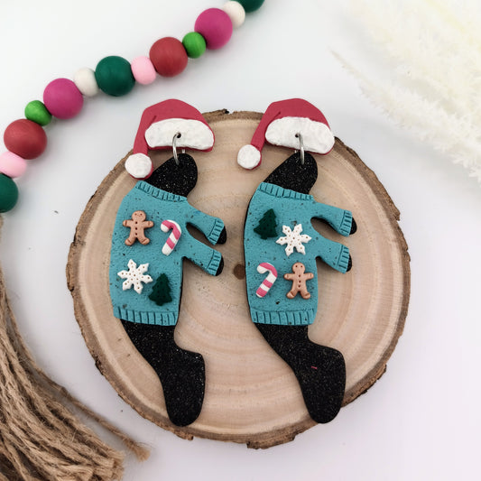 Pair of manatee Christmas-themed earrings on a wooden disc with colorful bead garland.