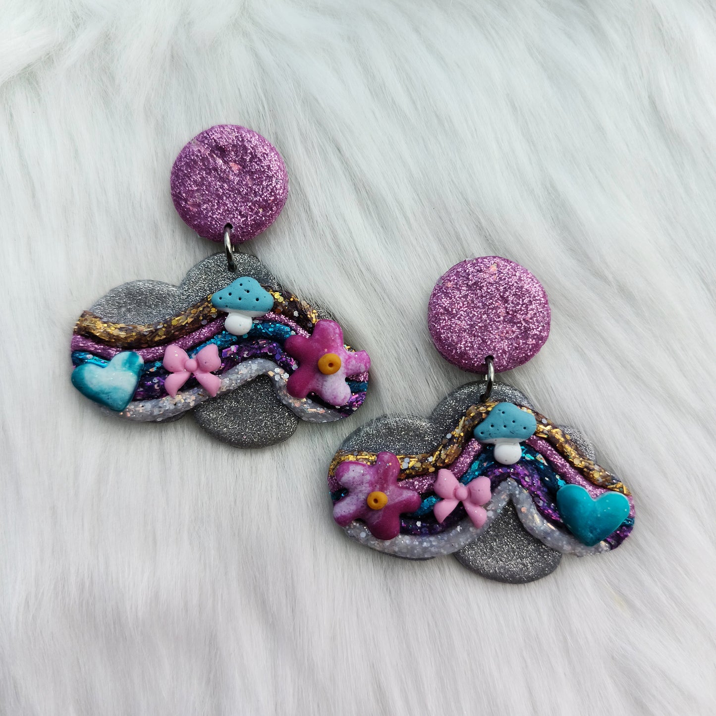 Colorful cloud-shaped earrings on a white fur background