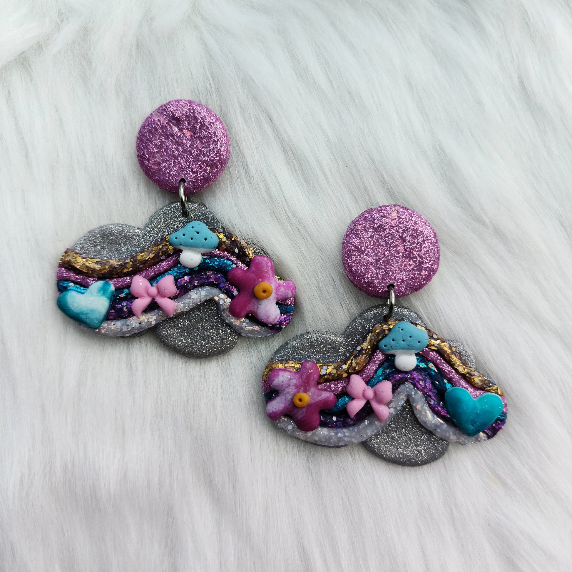 Colorful cloud-shaped earrings on a white fur background