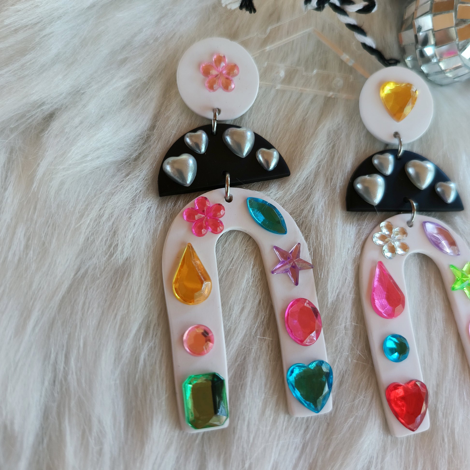 Colorful earrings with various shapes and patterns on a fur background.
