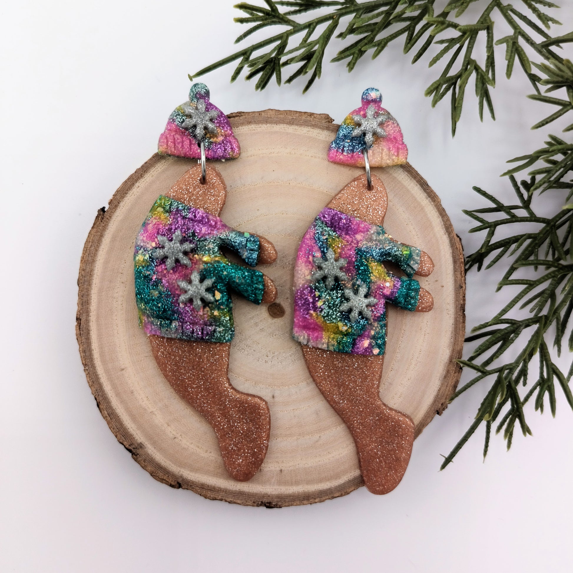 Colorful manatee earrings on a wooden slice with greenery