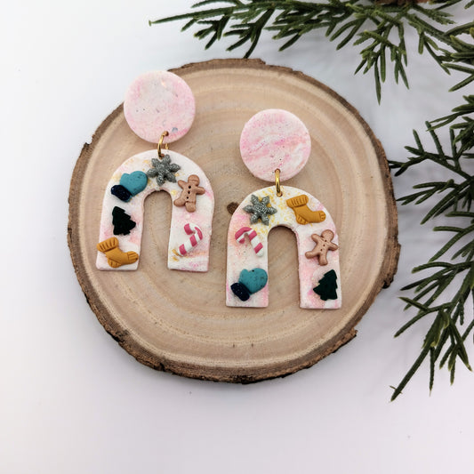 Decorative Christmas earrings on a wooden slice with greenery in the background