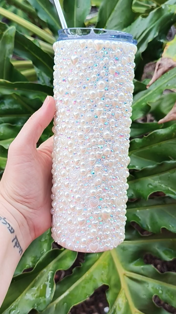 a video of the small details of this stainless-steel tumbler that is bedazzled with pearls, sparkly rhinestones, and pearl hearts of all sizes. Tumbler has a slide lid and metal straw. 