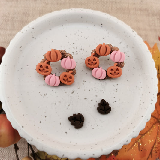 Pair of Halloween-themed earrings on a white speckled plate.
