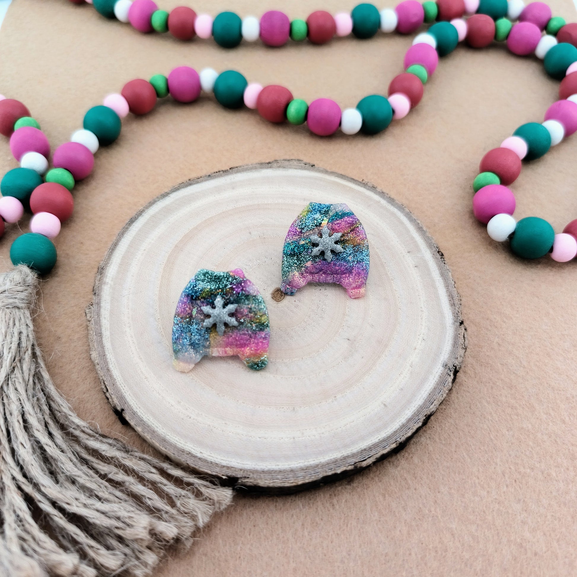 Colorful beaded garland with sparkle sweater earrings on a wooden surface
