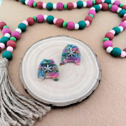 Colorful beaded garland with sparkle sweater earrings on a wooden surface