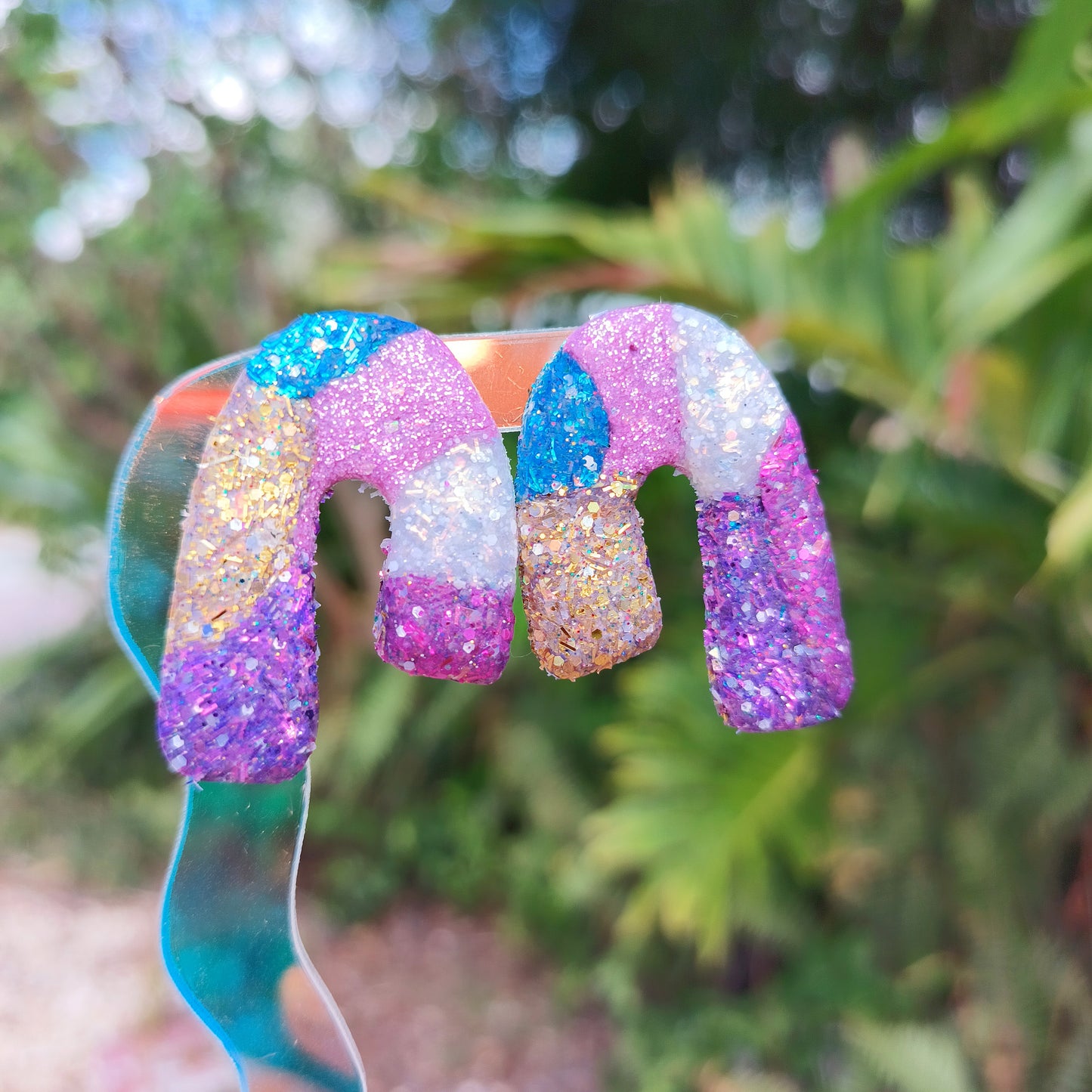 Glittery clay earrings with a blurred green background