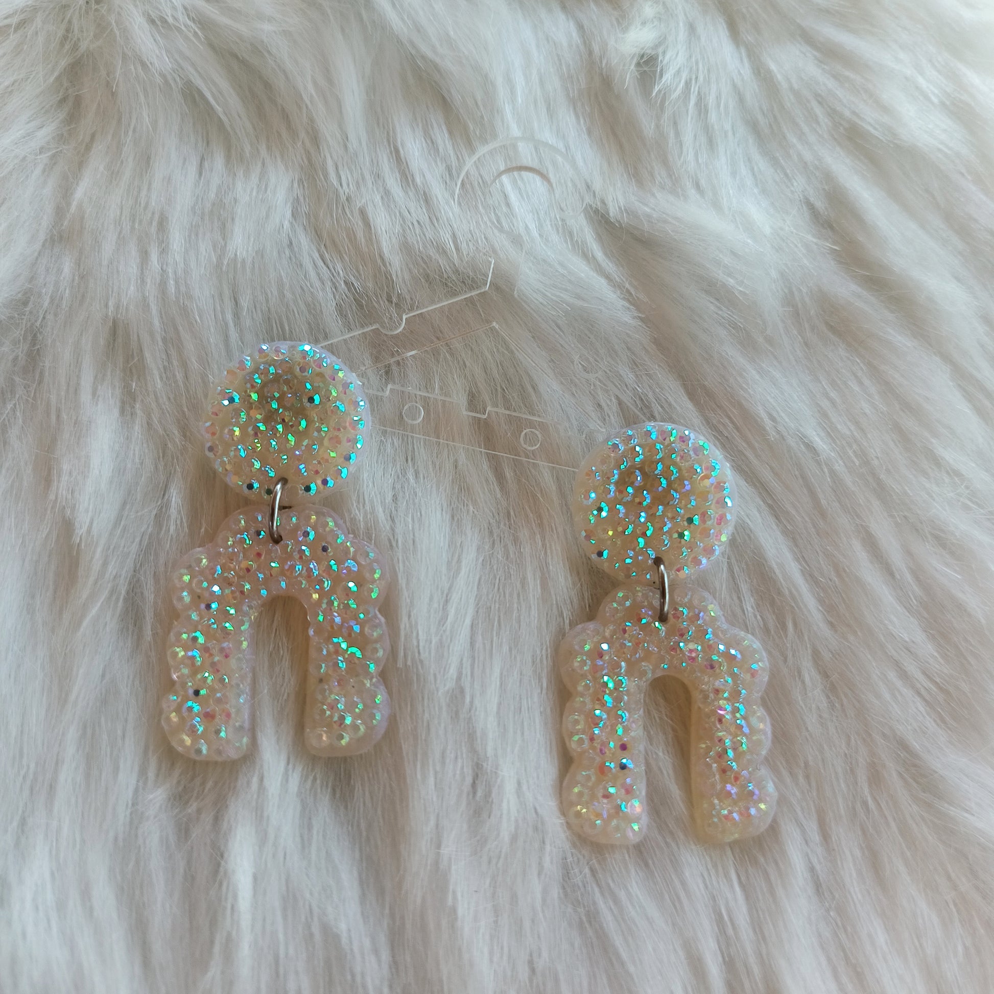 Pair of glittery earrings on a fluffy white surface
