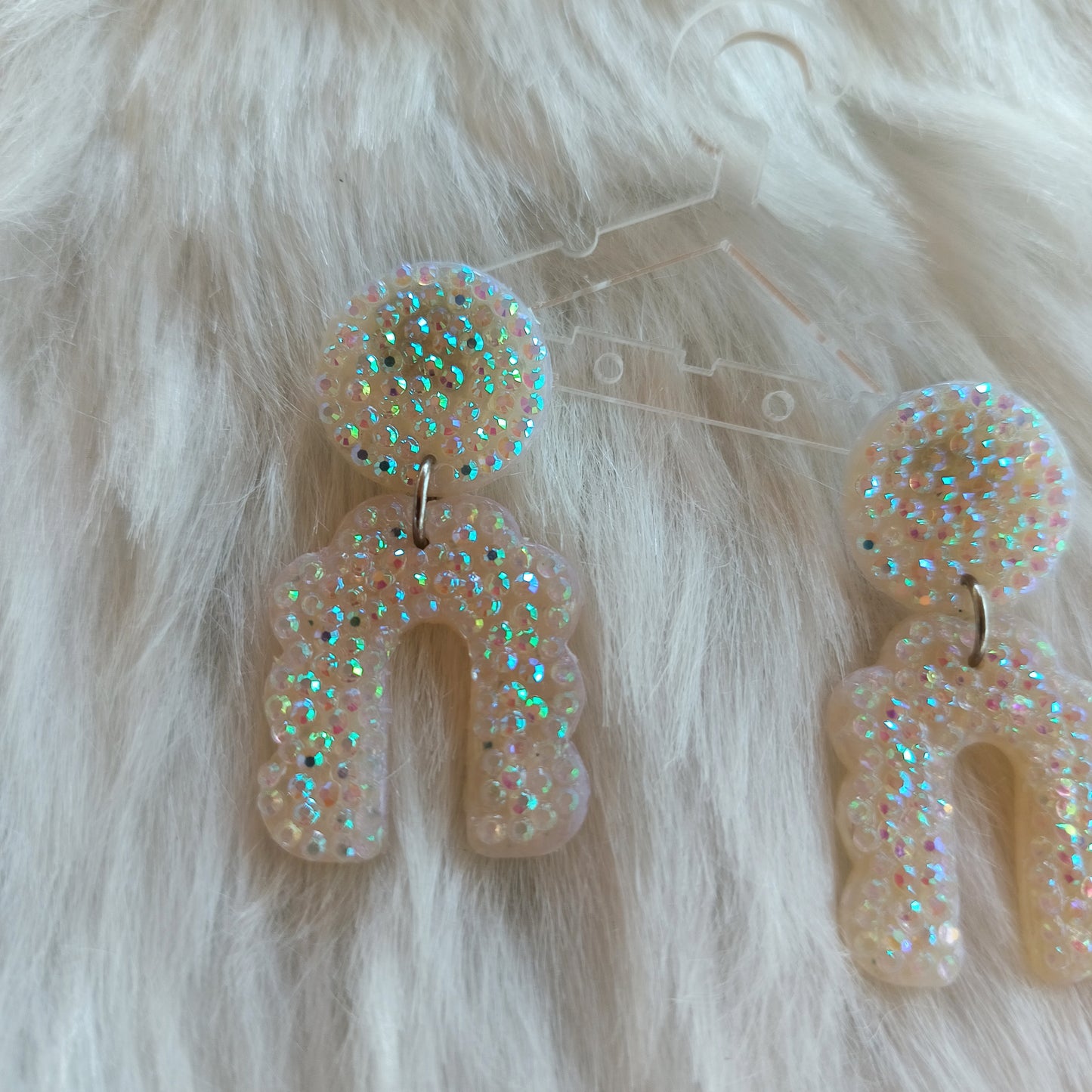Glittery earrings on a fluffy white surface