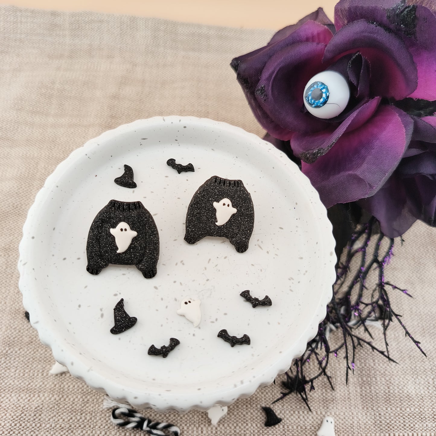 Halloween-themed earrings on a white dish with decorative elements.